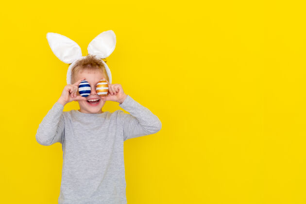 鸡蛋男孩头上戴着兔子耳朵 黄色的蛋上戴着彩色的蛋欢呼抱笑