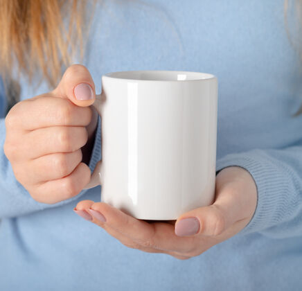 Coffee女性的手拿着模拟的白色空杯子 杯子为您的设计和标志特写促销短信或促销内容的模板空白cupHandLogo