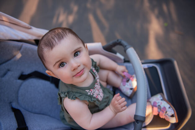 坐着一个可爱的小女婴穿着一件衣服 眼睛是绿色的 坐在一辆婴儿车里停车关门-一个小孩看着照相机的画像女儿童年女性