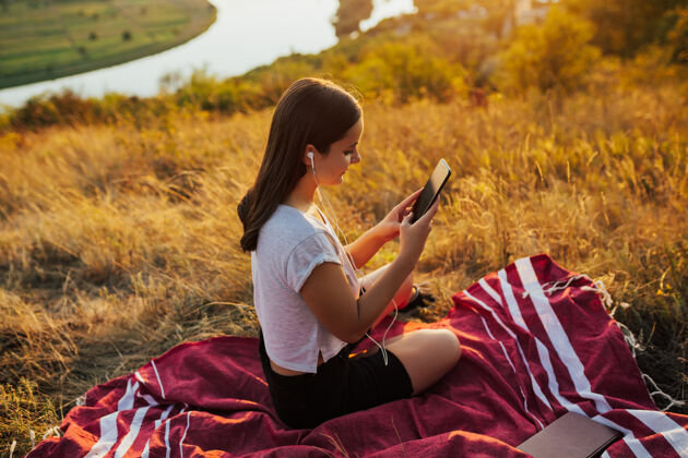 女孩快乐的女人坐在山上听最喜欢的歌电话健康享受