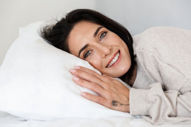 室内图为30多岁的白人妇女躺在床上 躺在家里的白色枕头上中年放松肖像