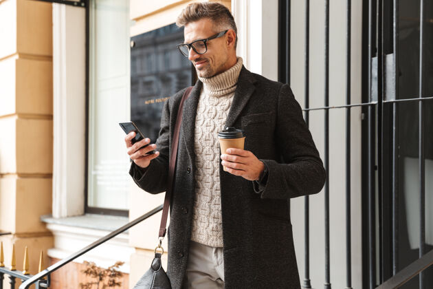 休闲帅哥穿着外套走在户外 用手机 喝咖啡教育户外街道