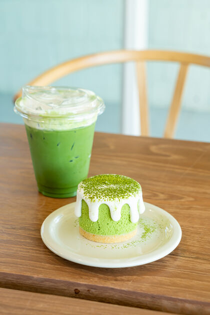 饮料在咖啡馆的桌子上放着一个绿茶芝士蛋糕和一个绿茶杯绉饼糕点健康的