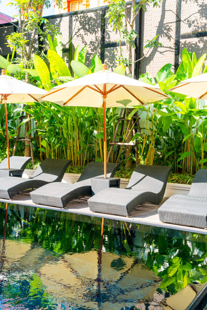 椰子伞和床游泳池周围的椅子游泳池-度假和旅游度假的概念温泉椅子休息室
