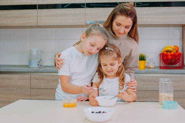 Muesli一位母亲和她的两个女儿在厨房里给燕麦片加蜂蜜生活饮食自然