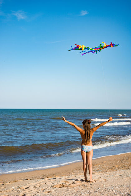 游戏两个快乐的小女孩带着风筝在海边的沙滩上奔跑风筝女孩妹妹