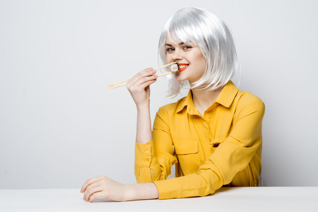 坐着白假发美女吃寿司卷餐厅用餐食物用餐