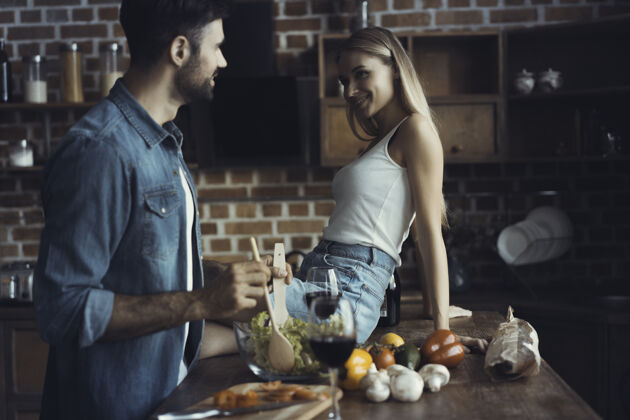 食物美丽的年轻夫妇在家里的厨房边喝酒边微笑成人木头薯条