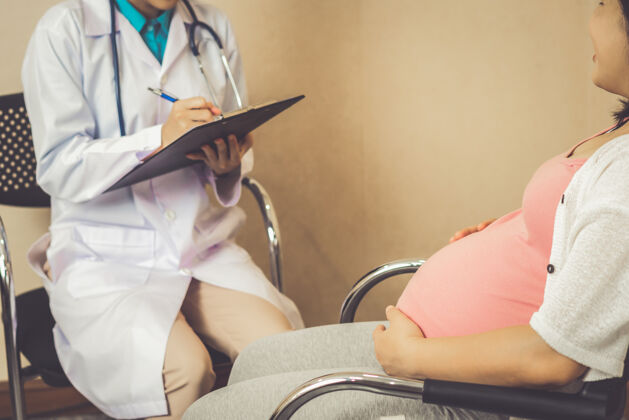 女性快乐的孕妇到医院或诊所找妇科医生做妊娠顾问肥料医生孩子