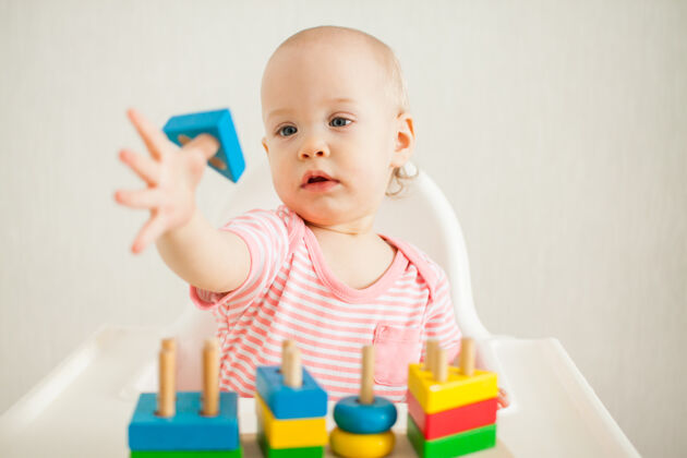 可爱小女孩玩着一个教育玩具——一个五颜六色的木制玩具金字塔发展太好了逻辑儿童发展兴趣