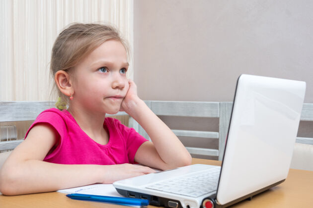 笔记本电脑可爱的小女生坐在桌边思考如何做作业电脑视频学习