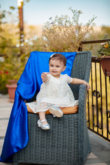 自然夏日坐在草椅上的可爱漂亮的宝宝的垂直镜头快乐头发座位