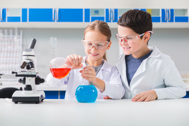室内好奇的头脑快乐又聪明的孩子们在学习科学的时候穿着实验服做实验研究测试化学家