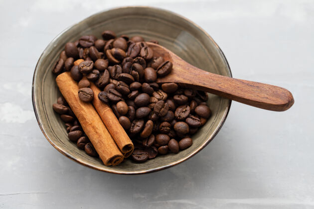 自然咖啡粒和肉桂用木勺盛在小碗里浓缩咖啡芳香能源