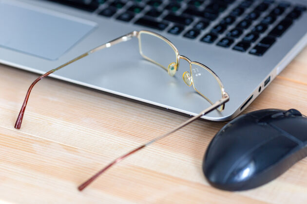 桌面眼镜放在办公室的笔记本电脑和桌面上教育镜头疲劳