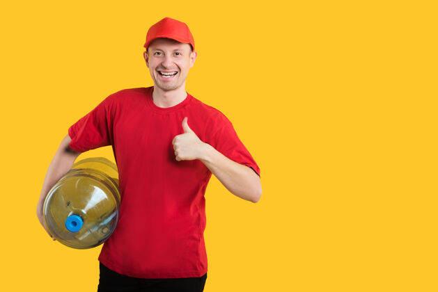 人快乐的信使穿着黄色的红色制服 拿着一瓶水竖起大拇指男男瓶子