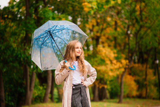 公园秋林伞下年轻迷人的微笑女孩围巾金发白色