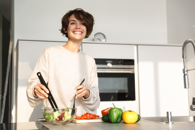室内一张快乐的黑发女人在厨房的桌子旁做饭的照片吸引室内休闲