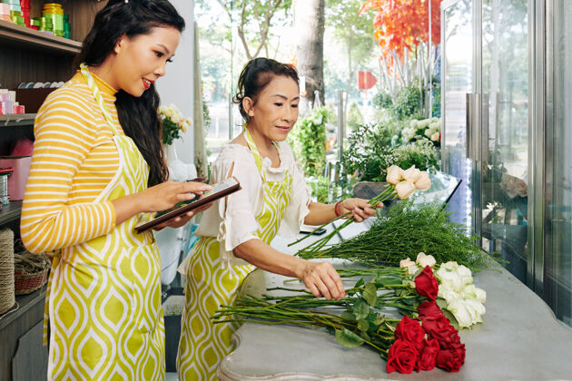购买花店老板在花店为顾客制作花束时 正在用平板电脑工作欢呼装饰员工