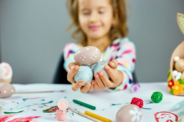 室内复活节那天可爱的小女孩手里拿着复活节彩蛋在明亮的背景上画彩蛋的女孩 复活节快乐显示童年复活节彩蛋