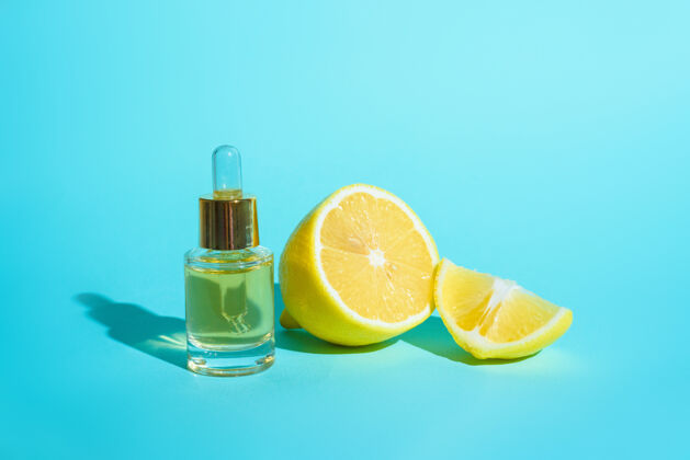 奶油脸上的精华液用柑橘类水果柠檬和维生素c装在一个玻璃瓶中 用移液管在蓝色的背景上 这是家里自我护理皮肤的概念美容护理新鲜