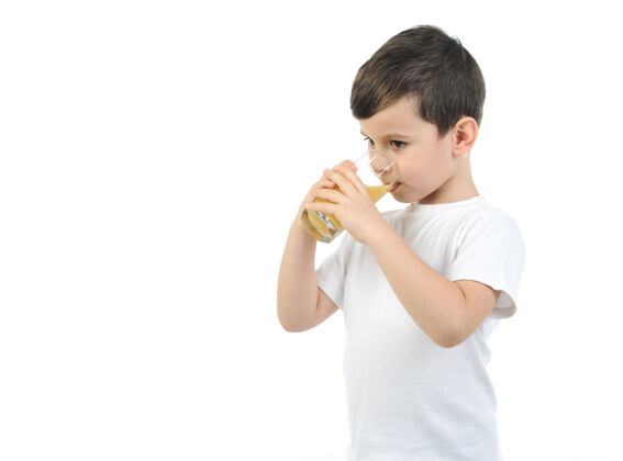儿童一个6岁的男孩穿着一件白色t恤 在一个白色的桌子上喝柑橘汁背景隔离背景果汁酒杯T恤