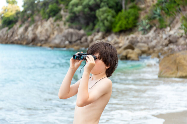 男性一个小男孩呆在海边 用望远镜看海滩发现旅行手表