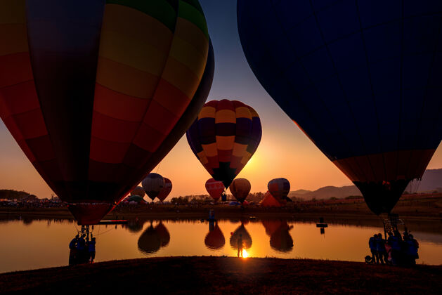 黎明夕阳下 热气球在山上和湖面上的剪影湖泊冒险山