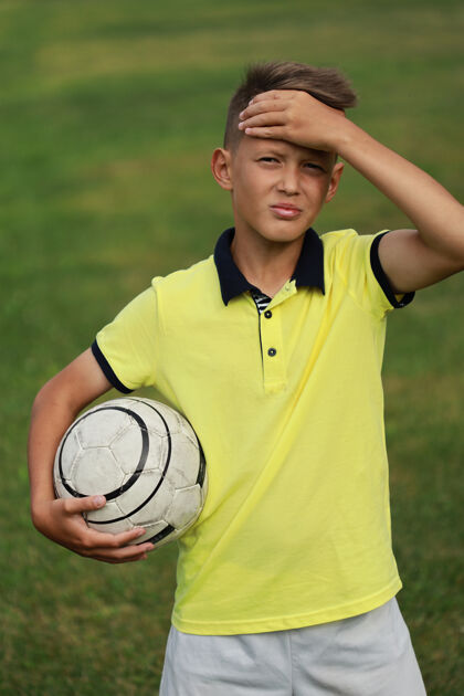 年轻穿着黄色t恤的帅哥足球运动员站在足球场上 手里拿着一个球竞争游戏男性