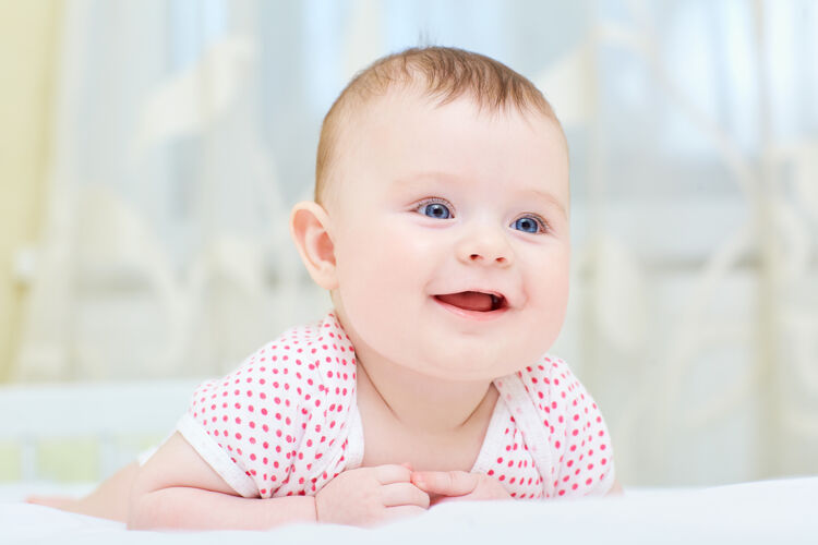 情绪婴儿 婴儿微笑着躺在白色的床上欢呼圈肖像