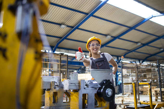 操作员工厂女工举着大拇指站在工业机器旁的画像工厂女性职业