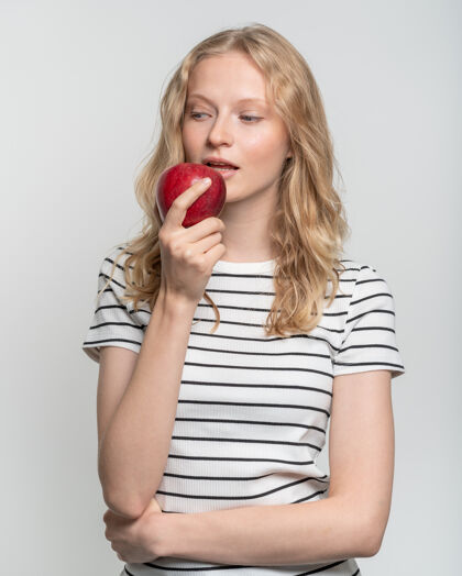 苹果微笑的年轻女子咬红的画像苹果新鲜的脸 自然美比特护理金发