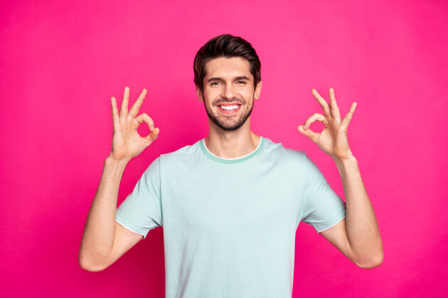 好搞笑男子汉的照片显示奥基符号表达同意和积极的态度穿休闲t恤孤立充满活力的粉红色背景手指脸可爱