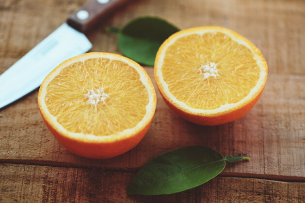 健康新鲜的橘子片和叶子健康的水果 橘子带叶子的水果菜刀放在木头上食物切片维生素