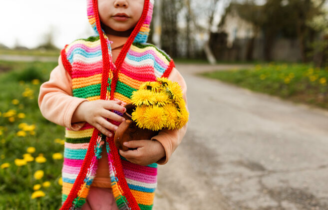 人一个穿着鲜艳多彩夹克的小女孩站在街上 手里捧着一束黄色的蒲公英宝贝脸明亮