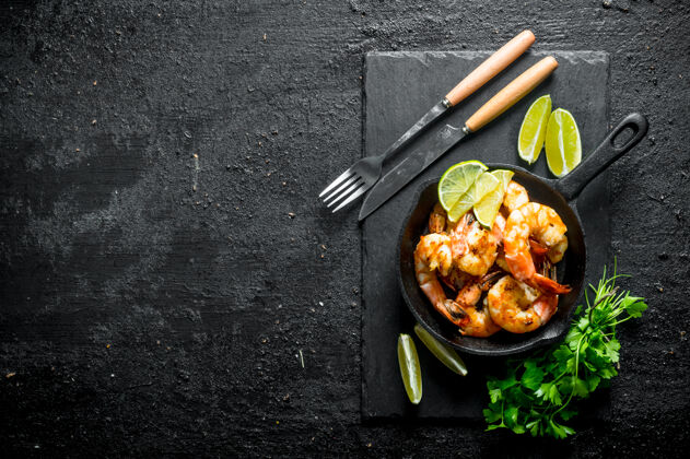 欧芹香喷喷的小虾放在石板上 欧芹和石灰放在黑木桌上新鲜小吃海