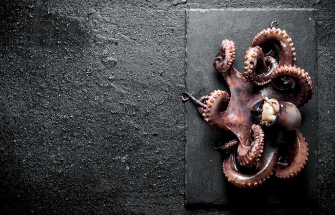 准备黑木桌上的石板上放着新鲜的章鱼腿食物晚餐