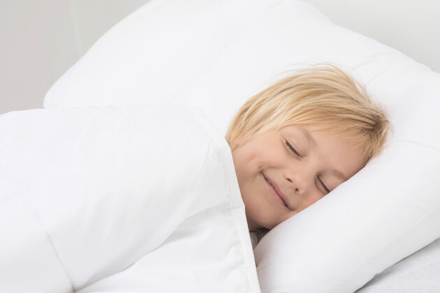 可爱可爱的小男孩安静地睡在床上 微笑着看着梦童年表情休息