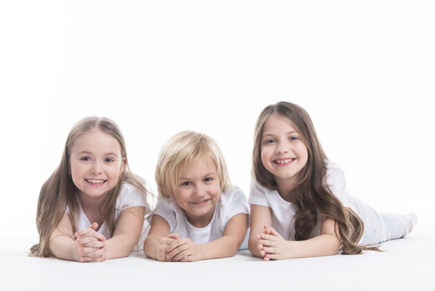 小三个穿着白衣服的孩子快乐地微笑着躺在地板上 隔着白墙乐趣家庭兄弟