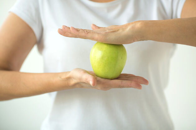 饮食女人一件白色t恤 白色背景上有一个苹果苹果营养肖像