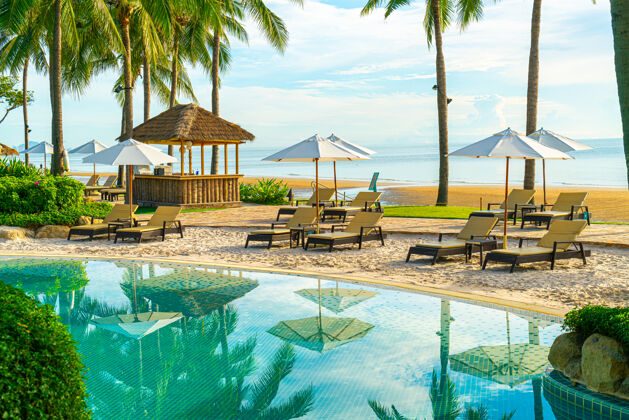 海滩美丽的豪华伞和椅子周围的室外游泳池在酒店和度假村椰子棕榈树日落或日出天空假日还有度假的概念伞度假度假村