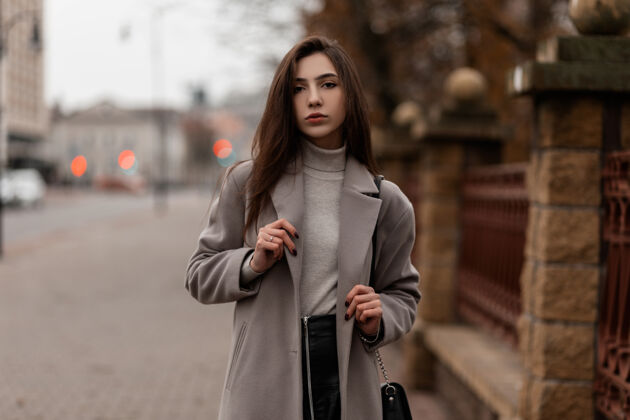 手提包优雅的模特 棕色的长发 穿着时髦的外套 在秋天的城市里摆姿势女人外套年轻