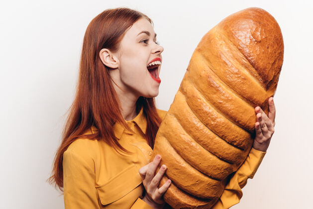 用餐一个惊讶的女人在轻墙上检查手里的面包吃大面包