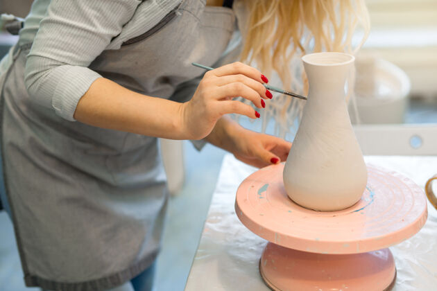 专业美丽的年轻女子在陶艺作坊里画陶罐商业手工形式
