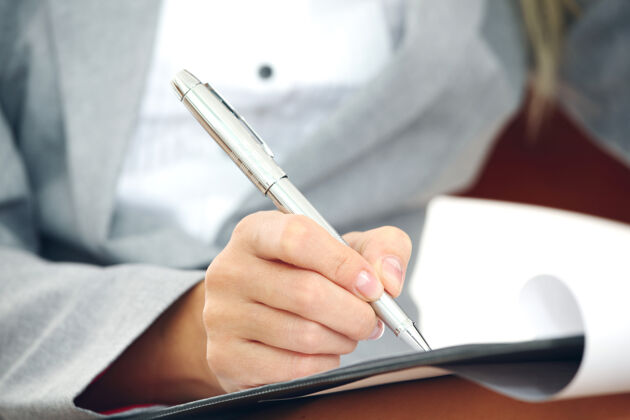 笔记西装革履的女商人用笔在文件纸上写笔记钢笔员工公司