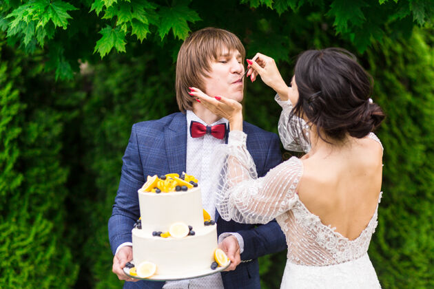 情侣新婚夫妇和伴娘们在婚宴上尽情享受 在新鲜空气中一起吃结婚蛋糕美丽乐趣一起
