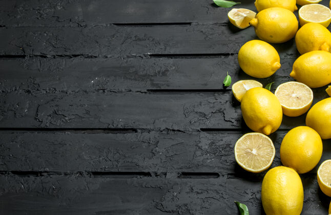 块成熟多汁的柠檬放在黑色乡村餐桌上顶视图美丽成熟