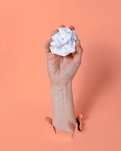 文件女人的手把揉成团的纸团扔进撕破的粉色纸里背景：极简主义理念皱纹办公室空白