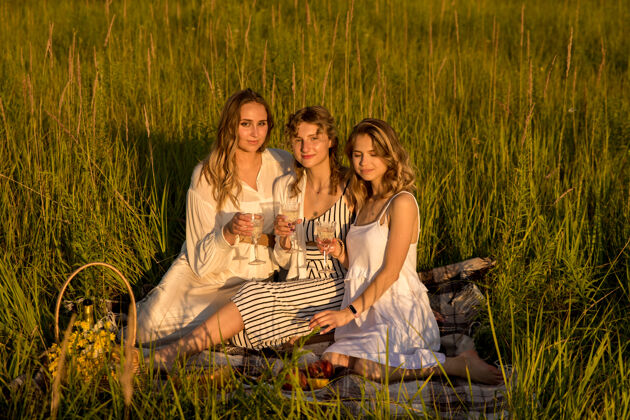 金发女友们在绿草野餐时喝香槟外地妇女开怀大笑女性自然夏天