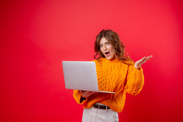 学生穿红色衣服的年轻女子手里拿着一台笔记本电脑肖像笔记本电脑年轻